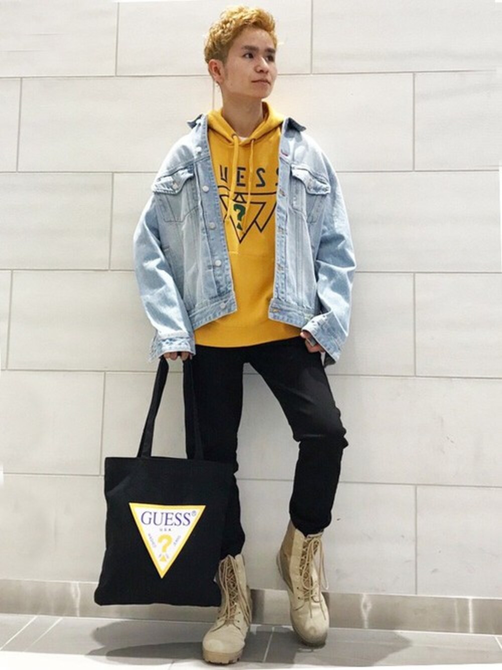 ブルー系のデニムジャケット、イエロー系のパーカー、ブラック系のトートバッグを着用したメンズの冬コーディネートの1枚目の写真