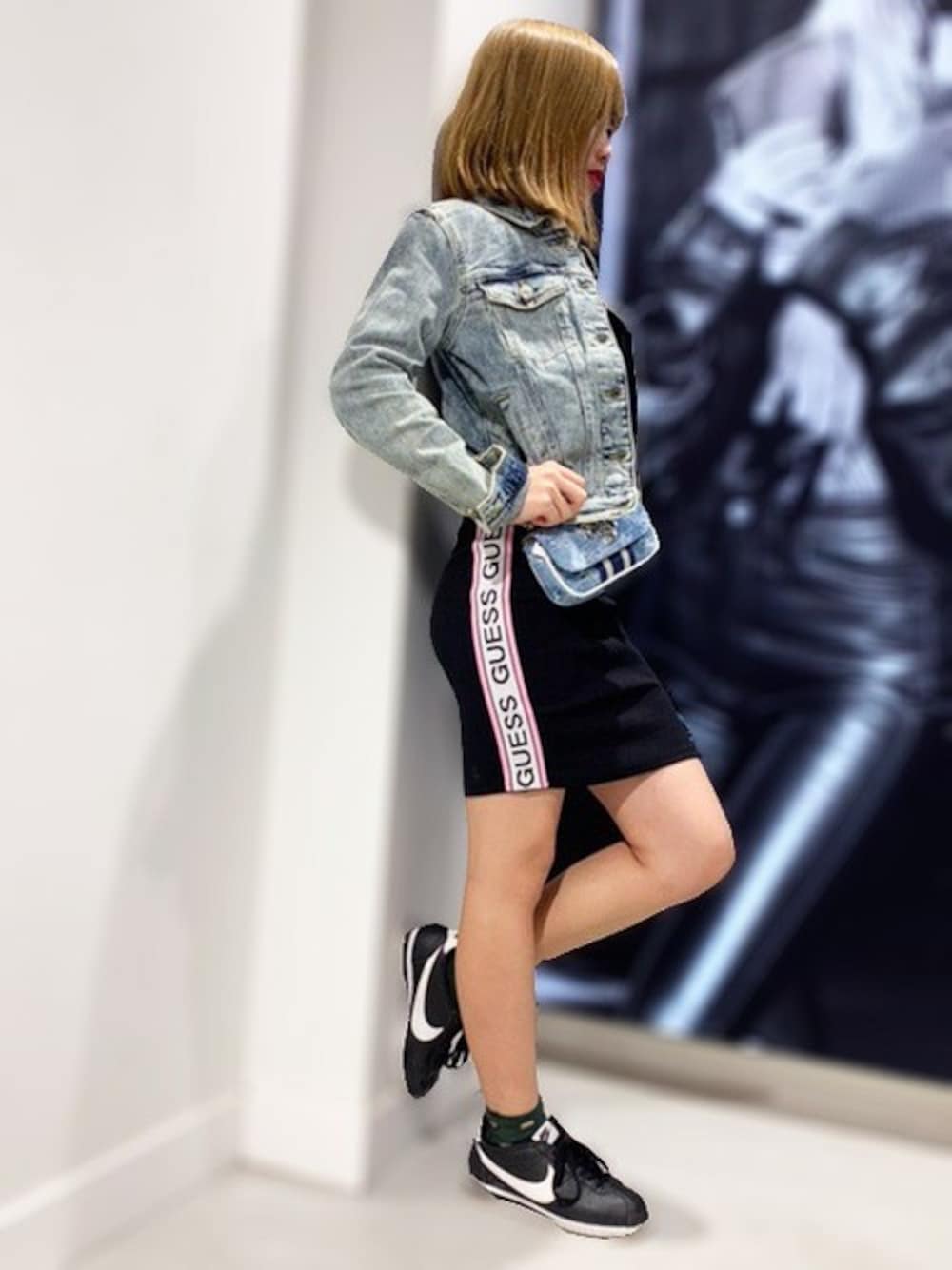 ブルー系のショルダーバッグ、ブルー系のデニムジャケット、ブラック系のワンピースを着用したレディースの冬コーディネートの1枚目の写真