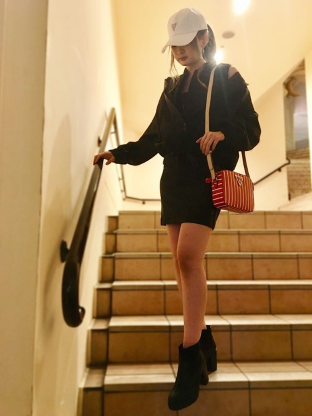 ブラック系のナイロンジャケット、ホワイト系のキャップを着用したレディースの冬コーディネートの1枚目の写真