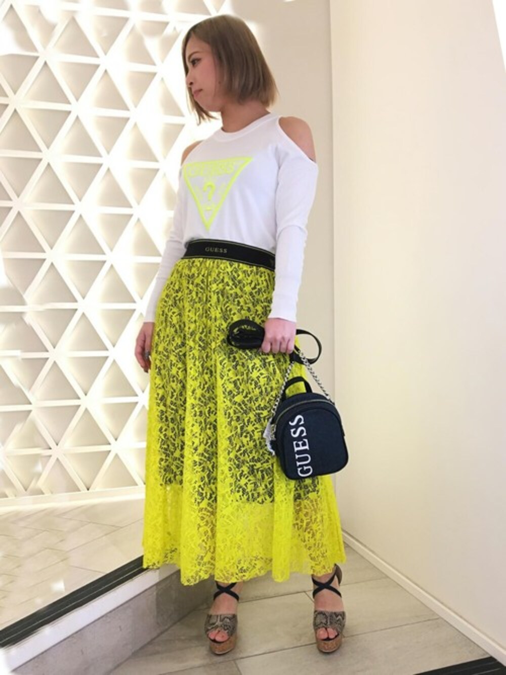 ホワイト系のニット/セーター、ブルー系のショルダーバッグ、イエロー系のスカートを着用したレディースの冬コーディネートの1枚目の写真