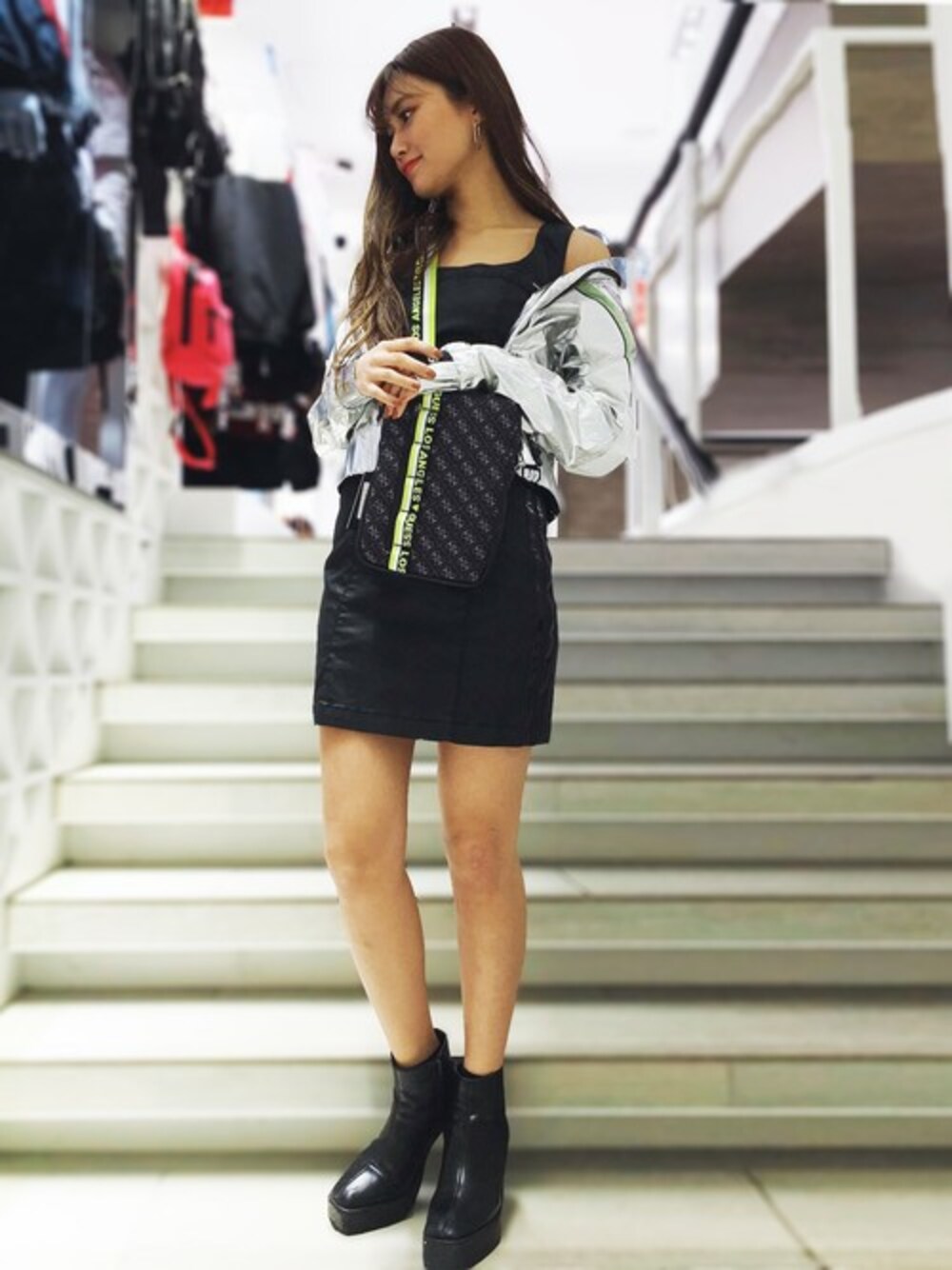 ブラック系のワンピース、シルバー系のナイロンジャケットを着用したレディースの春コーディネートの1枚目の写真