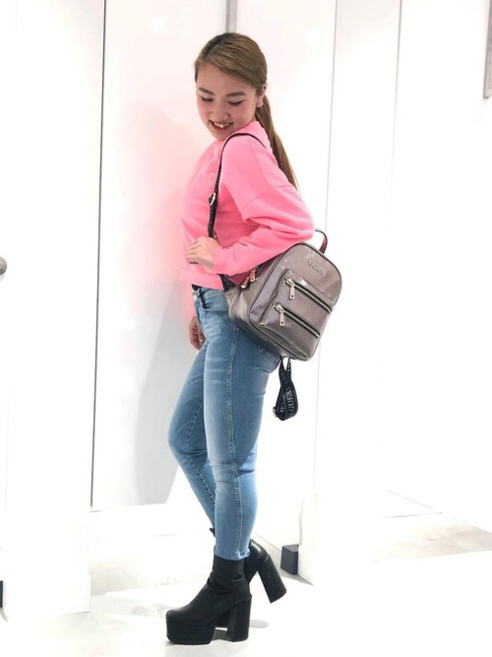 ブルー系のデニムパンツ、ピンク系のスウェット、ピンク系のバックパック/リュックを着用したレディースの春コーディネートの1枚目の写真