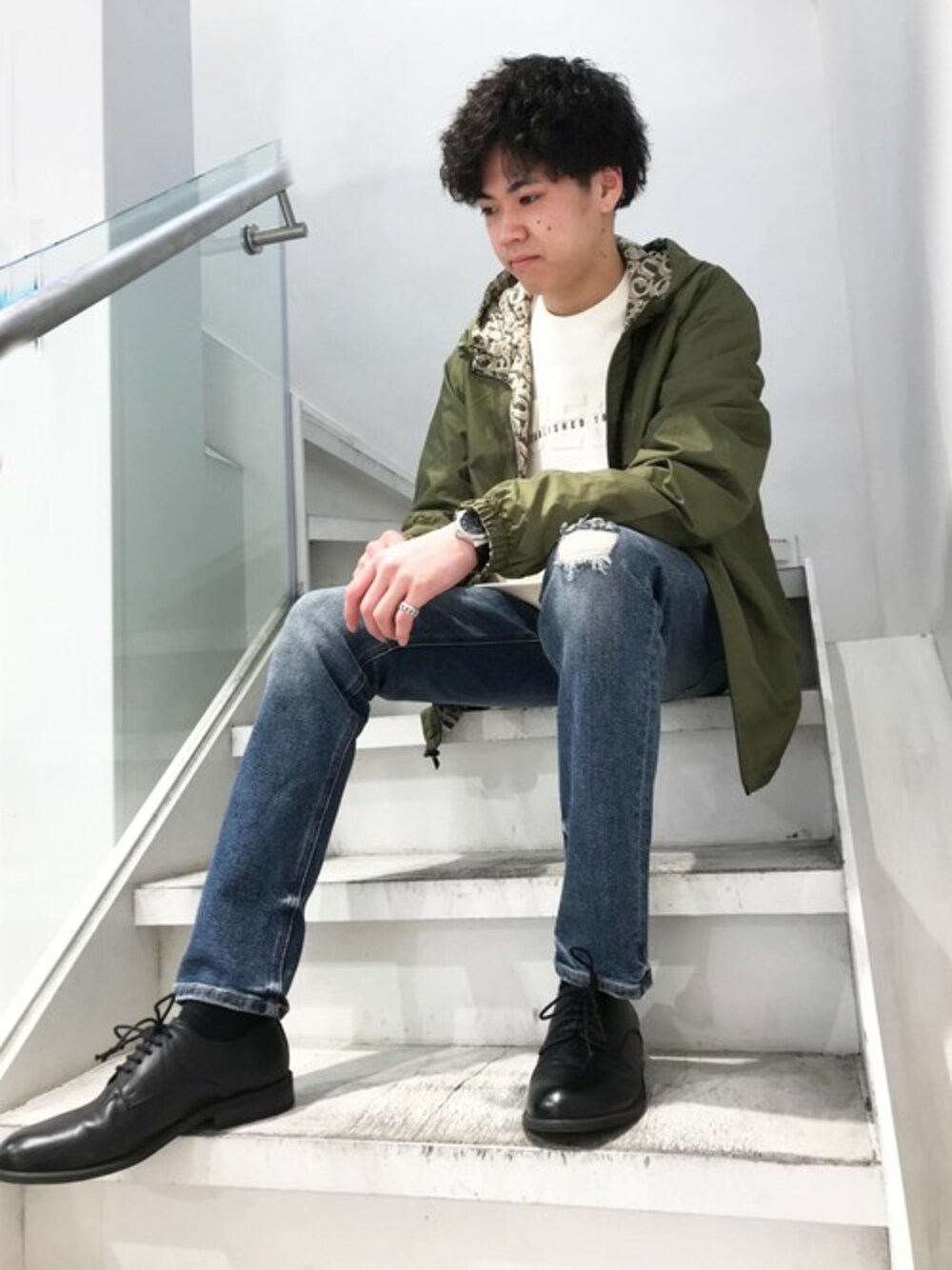 ブラック系のスウェット、グリーン系のナイロンジャケット、ブルー系のデニムパンツを着用したメンズの春コーディネートの1枚目の写真