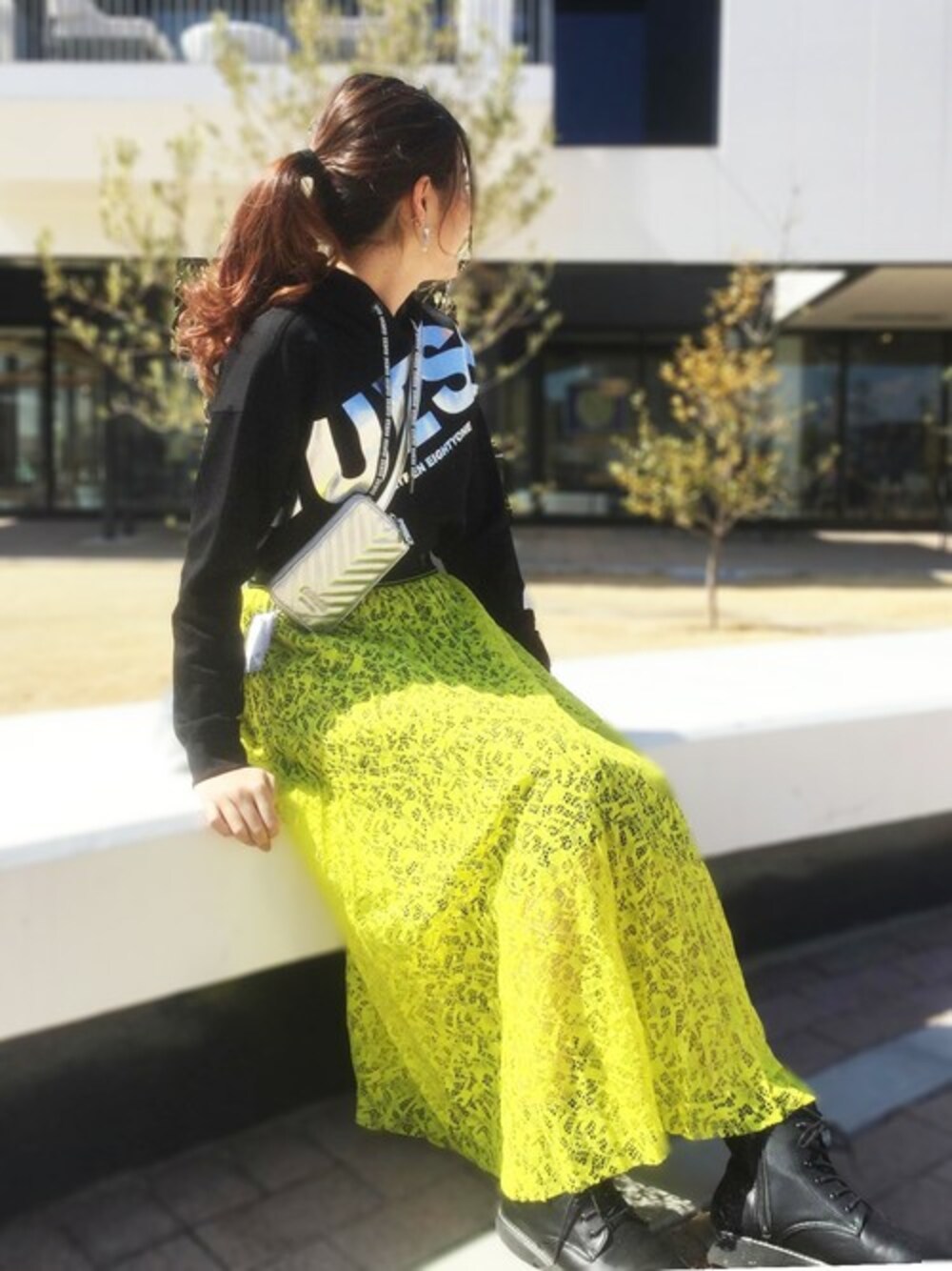 ブラック系のパーカー、イエロー系のスカートを着用したレディースの春コーディネートの1枚目の写真