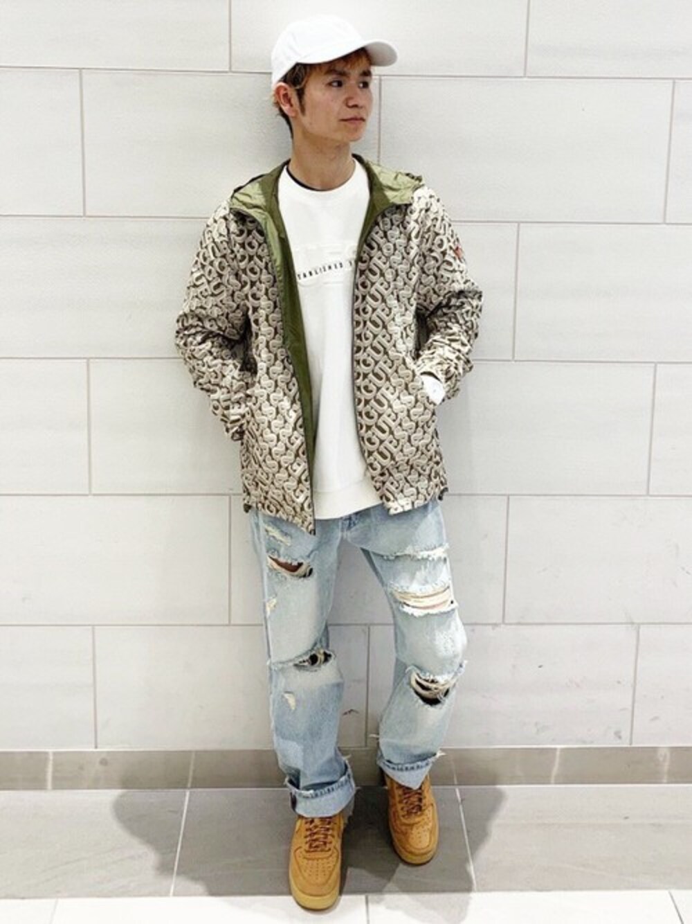 グリーン系のナイロンジャケット、ホワイト系のスウェット、ブルー系のデニムパンツを着用したレディースの春コーディネートの1枚目の写真