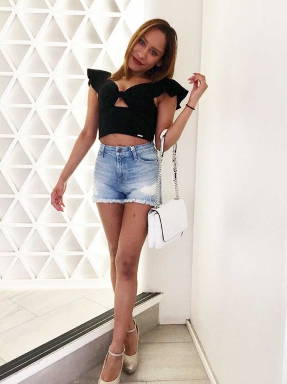 ブラック系のTシャツ/カットソー、ブルー系のデニムパンツ、ホワイト系のハンドバッグを着用したレディースの春コーディネートの1枚目の写真