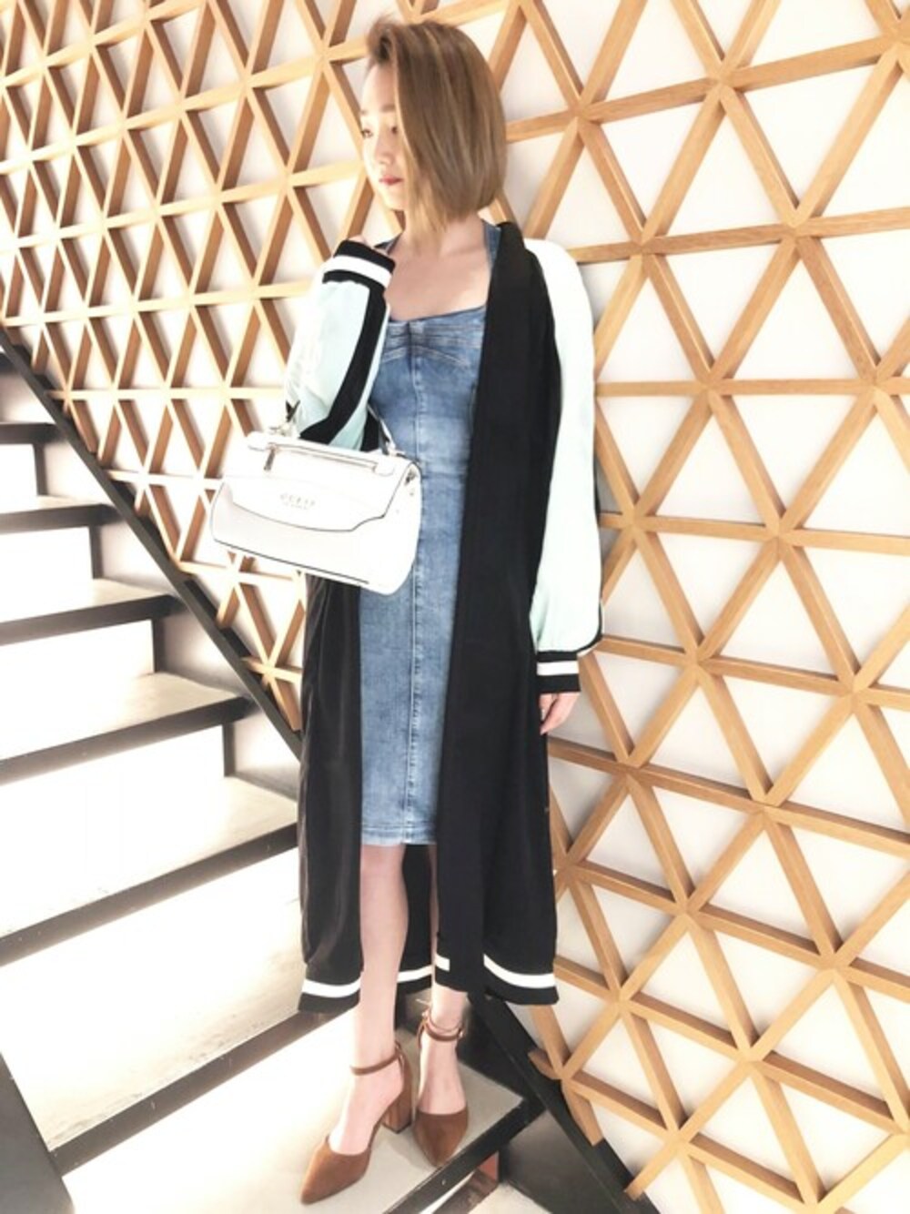 ブラック系のその他アウター、ブルー系のワンピース、ホワイト系のハンドバッグを着用したレディースの春コーディネートの1枚目の写真