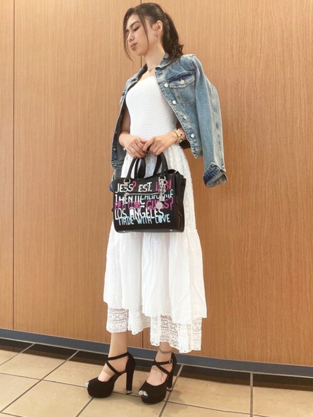 ブルー系のデニムジャケット、ブラック系のハンドバッグを着用したレディースの夏コーディネートの1枚目の写真