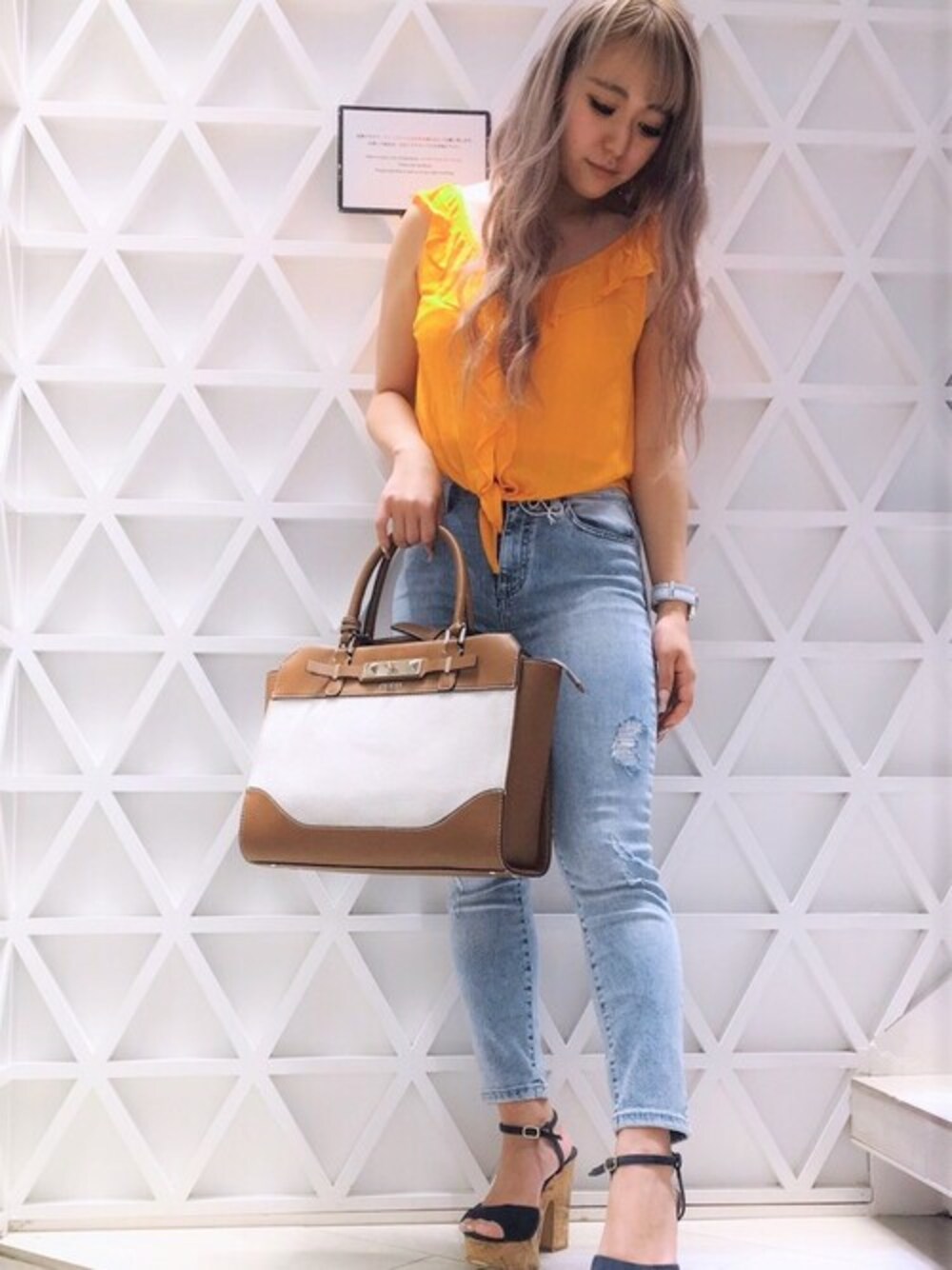 オレンジ系のタンクトップ、ブルー系のデニムパンツ、ブラウン系のトートバッグを着用したレディースの夏コーディネートの1枚目の写真