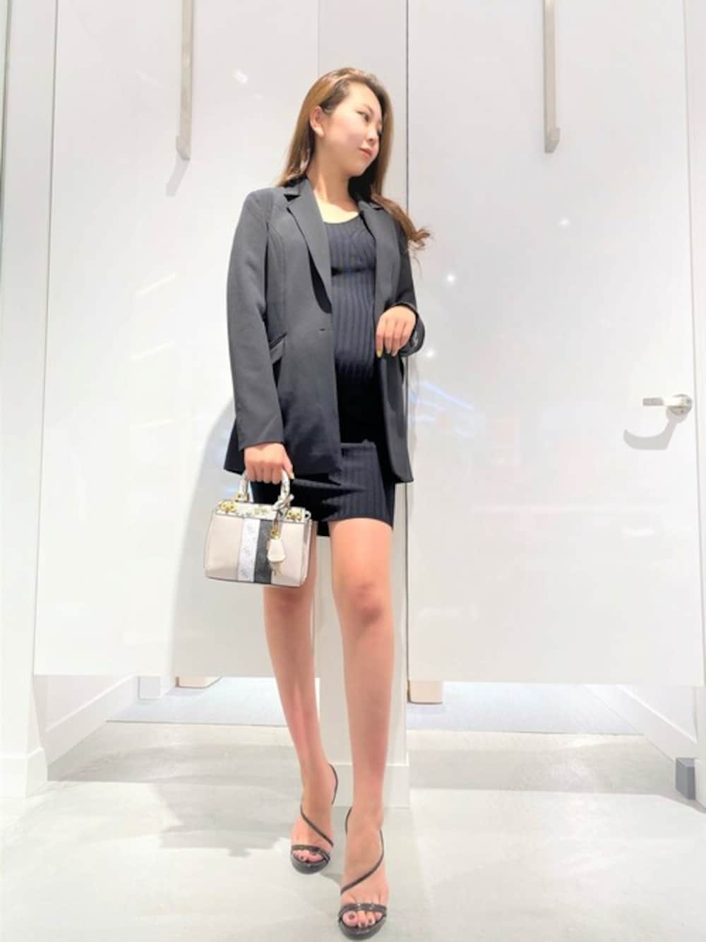 ブラック系のワンピース、ブラック系のテーラードジャケット、ホワイト系のハンドバッグを着用したレディースの秋コーディネートの1枚目の写真