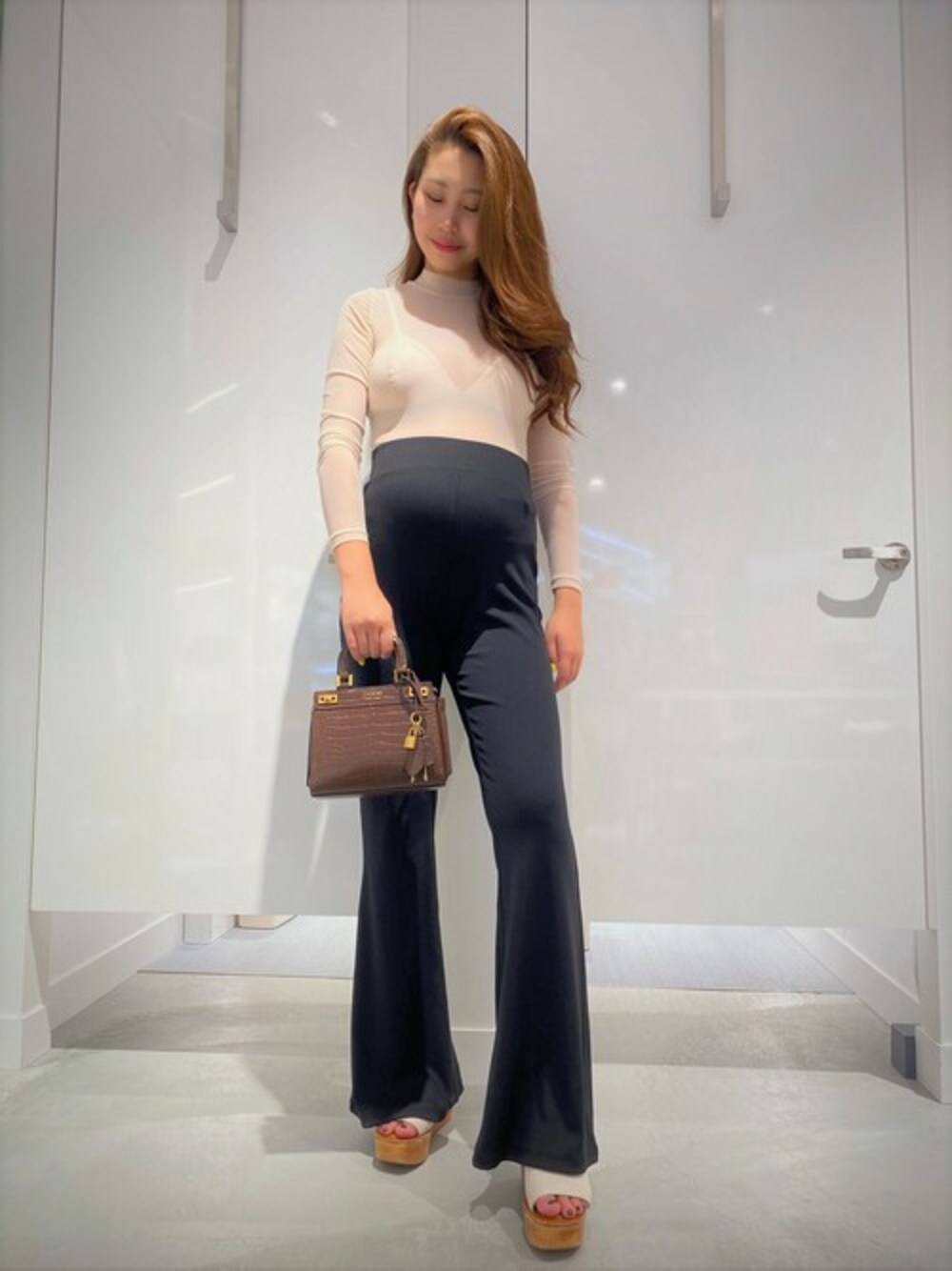 ピンク系のその他トップス、ブラック系のその他パンツ、ブラウン系のハンドバッグを着用したレディースの秋コーディネートの1枚目の写真