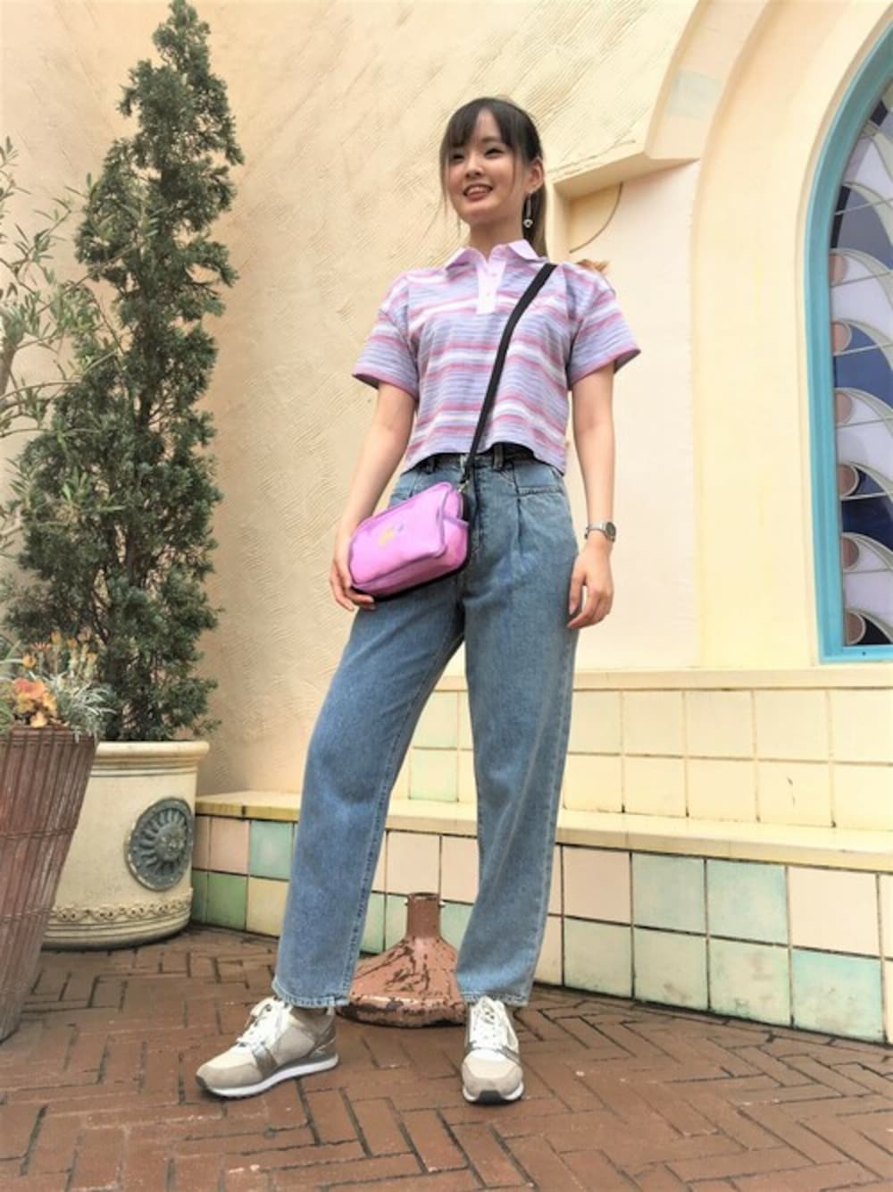 パープル系のポロシャツ、ブルー系のデニムパンツ、ピンク系のショルダーバッグを着用したレディースの秋コーディネートの1枚目の写真