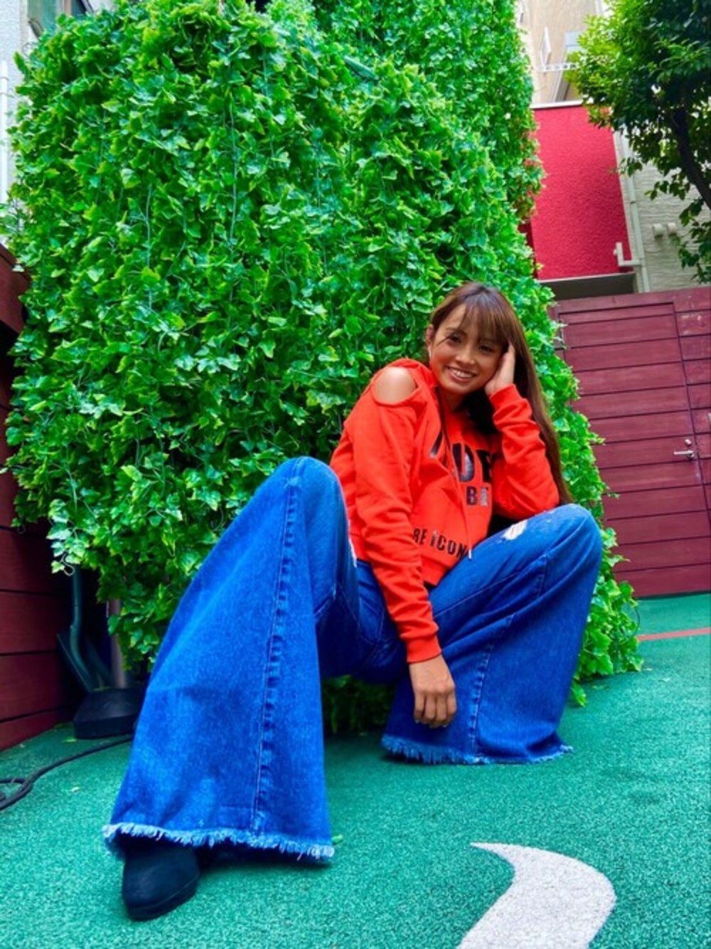 オレンジ系のパーカー、ブルー系のデニムパンツを着用したレディースの秋コーディネートの1枚目の写真