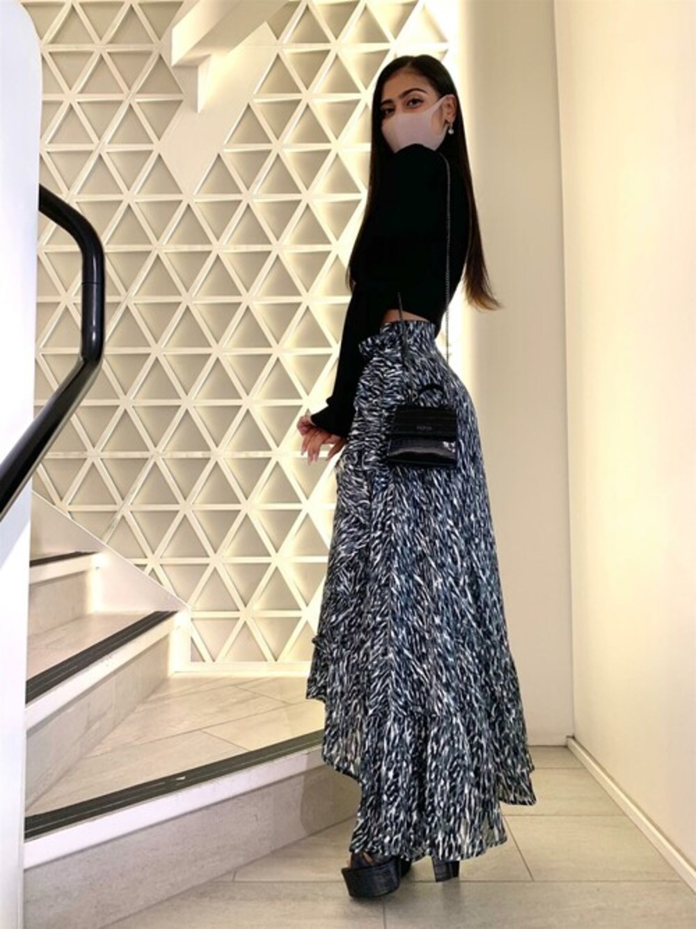 ブラック系のニット/セーター、ブラック系のスカート、ブラック系のショルダーバッグを着用したレディースの秋コーディネートの1枚目の写真