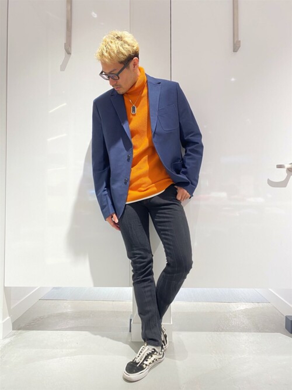 オレンジ系のニット/セーター、ブルー系のテーラードジャケット、ブラック系のデニムパンツを着用したメンズの冬コーディネートの1枚目の写真