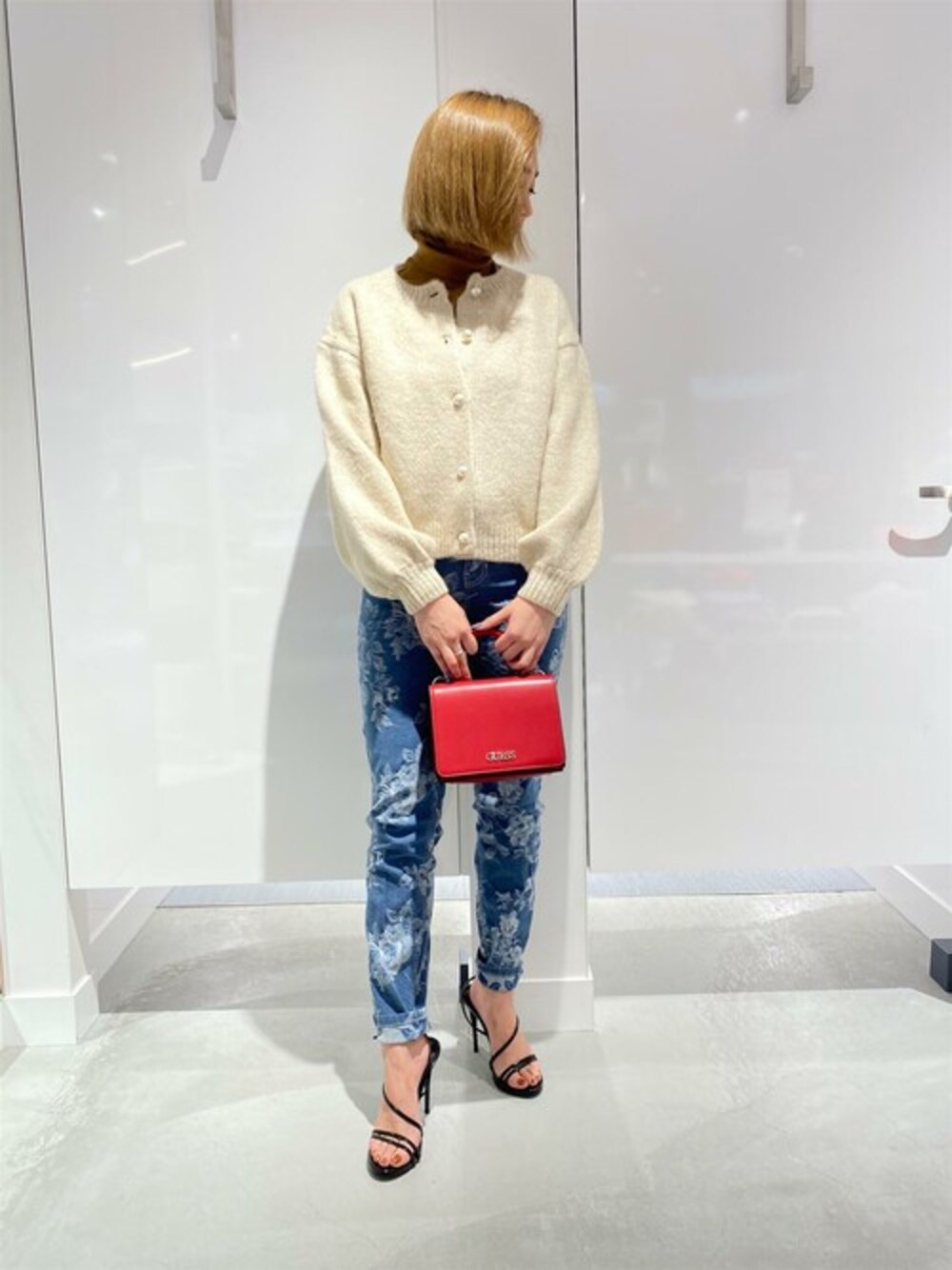 ブルー系のデニムパンツ、レッド系のショルダーバッグを着用したレディースの冬コーディネートの1枚目の写真