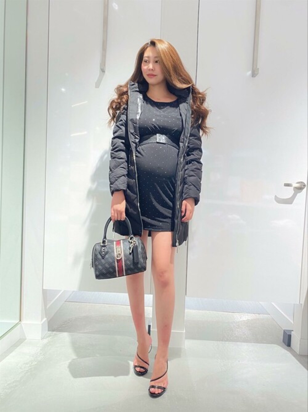 ブラック系のワンピース、ブラック系のその他アウター、グレー系のハンドバッグを着用したレディースの冬コーディネートの1枚目の写真