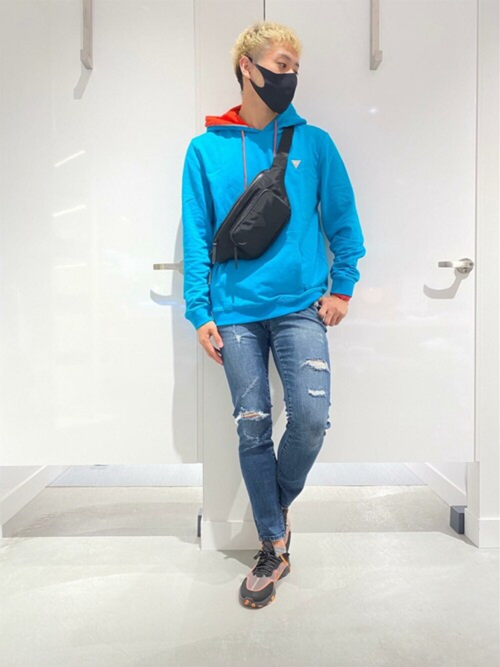 ブルー系のパーカー、ブルー系のデニムパンツ、ブラック系のボディバッグ/ウエストポーチを着用したメンズの冬コーディネートの1枚目の写真