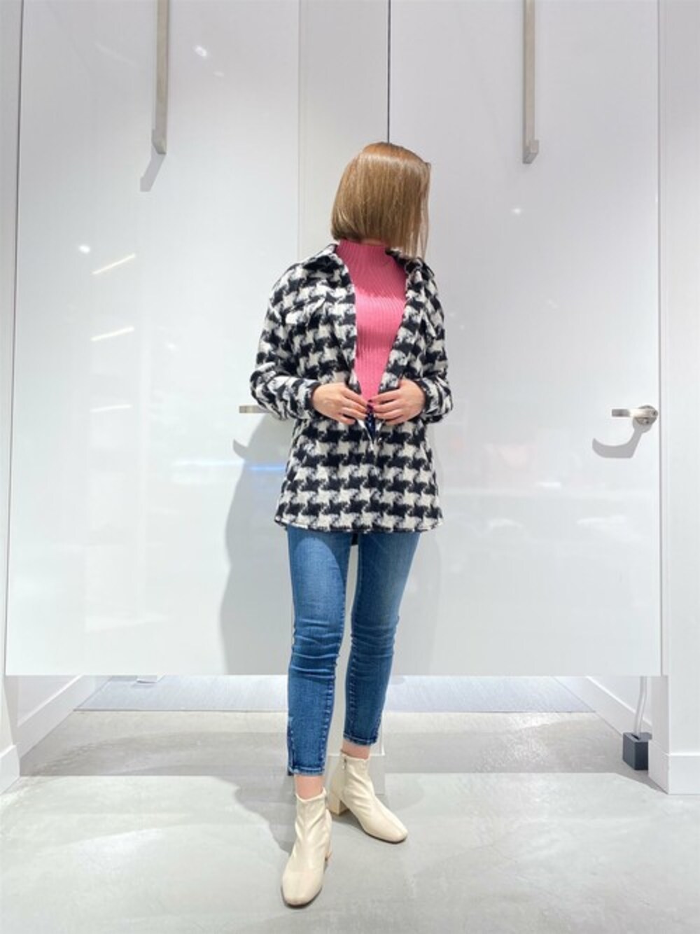 ピンク系のニット/セーター、ブラック系のその他アウター、ブルー系のデニムパンツを着用したレディースの冬コーディネートの1枚目の写真