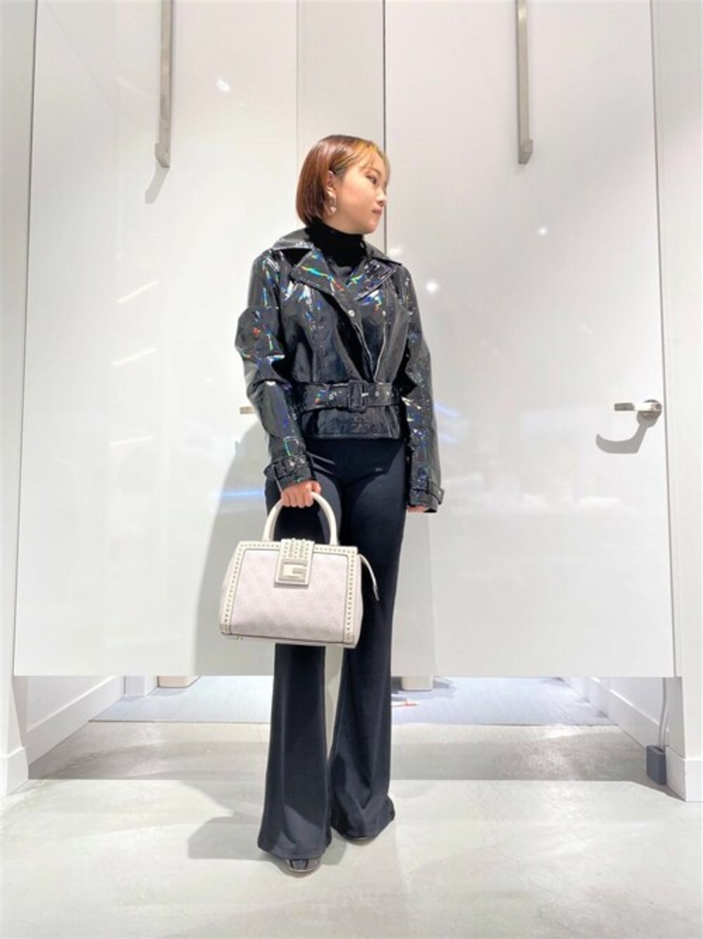 ブラック系のその他アウター、ブラック系のその他パンツ、ホワイト系のハンドバッグを着用したレディースの冬コーディネートの1枚目の写真