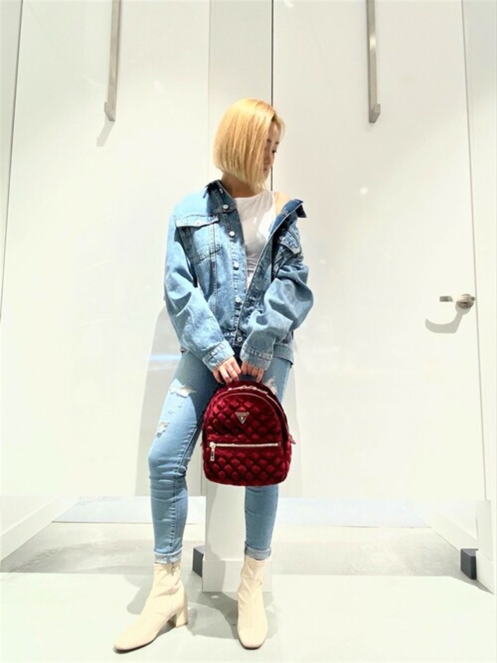 ブルー系のデニムジャケット、ブルー系のデニムパンツ、レッド系のバックパック/リュックを着用したレディースの冬コーディネートの1枚目の写真