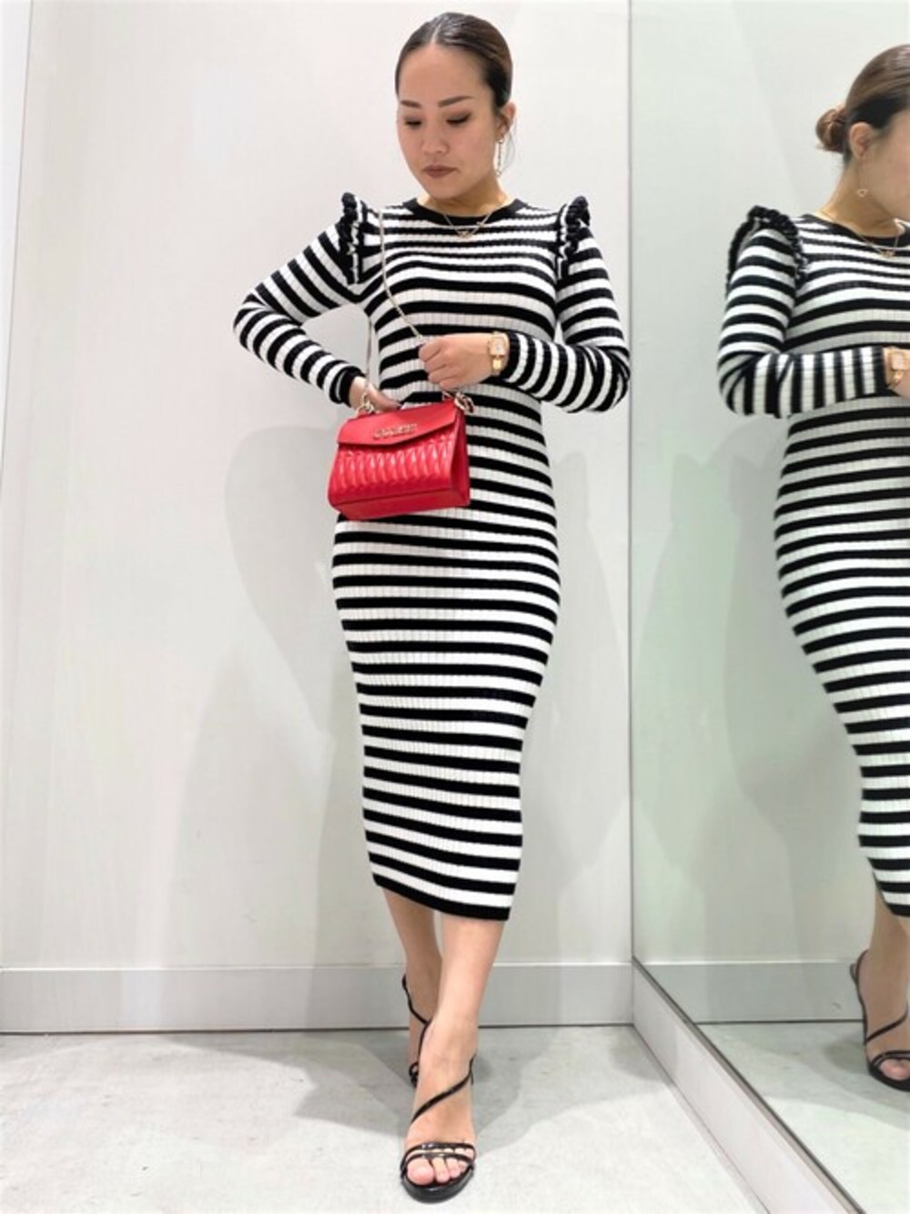 ブラック系のワンピース、レッド系のハンドバッグ、ゴールド系のピアス(両耳用)を着用したレディースの冬コーディネートの1枚目の写真