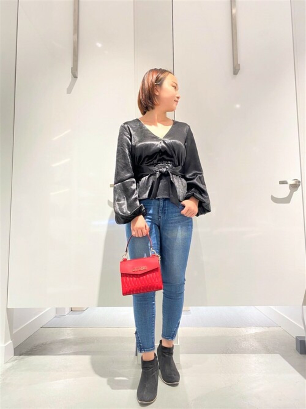 ブラック系のその他トップス、ブルー系のデニムパンツ、レッド系のハンドバッグを着用したレディースの冬コーディネートの1枚目の写真