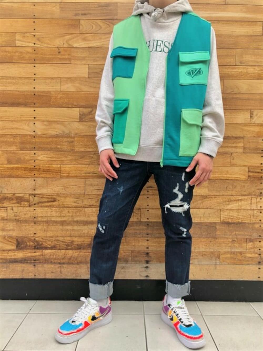 グレー系のパーカー、グリーン系のベスト、ブルー系のデニムパンツを着用したメンズの冬コーディネートの1枚目の写真