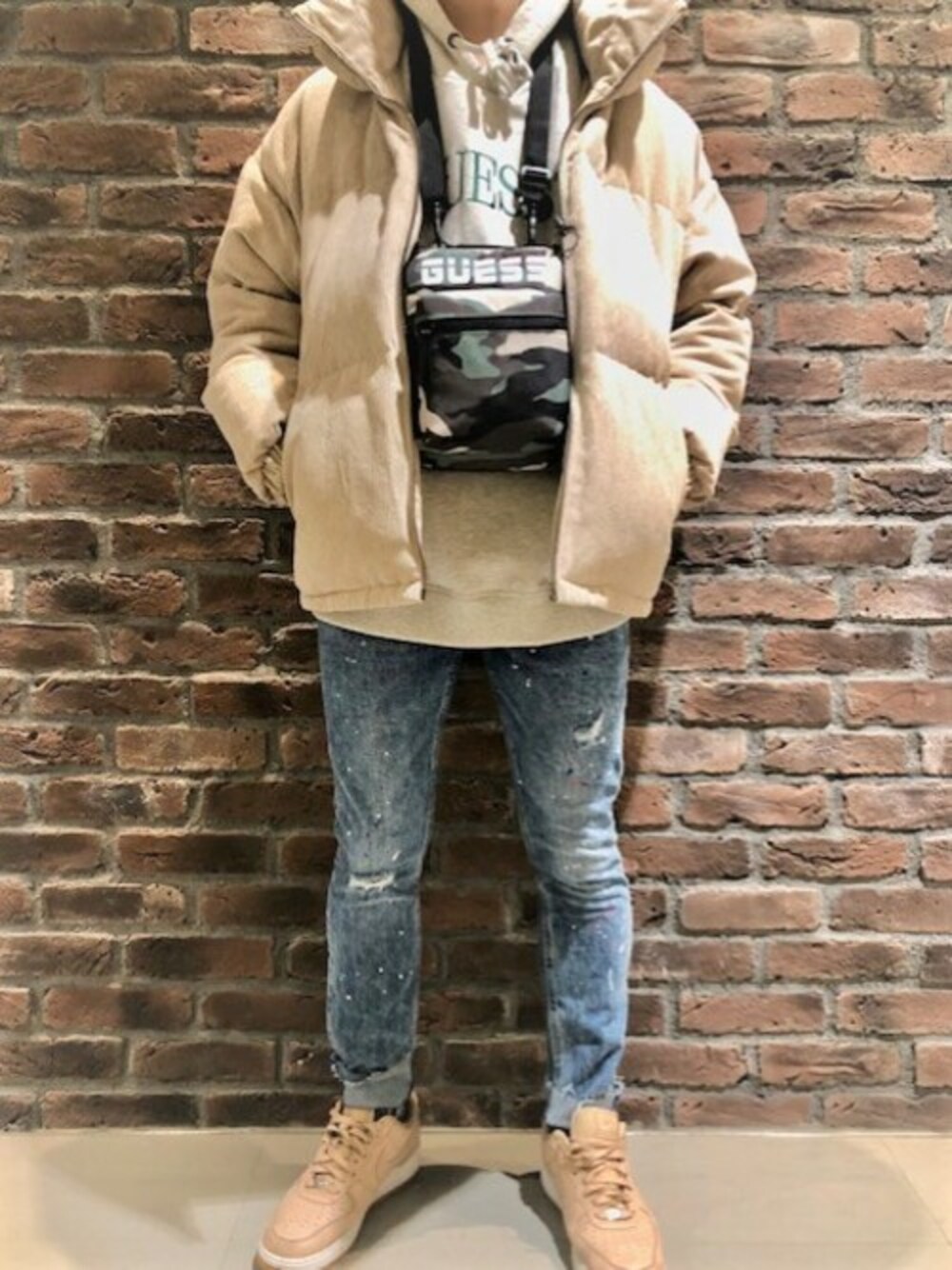 グレー系のパーカー、ベージュ系のダウンジャケット/コート、ブルー系のデニムパンツを着用したメンズの冬コーディネートの1枚目の写真