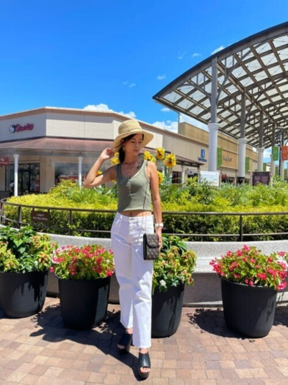 グリーン系のタンクトップ、ホワイト系のデニムパンツ、ブラウン系のショルダーバッグを着用したレディースの夏コーディネートの1枚目の写真