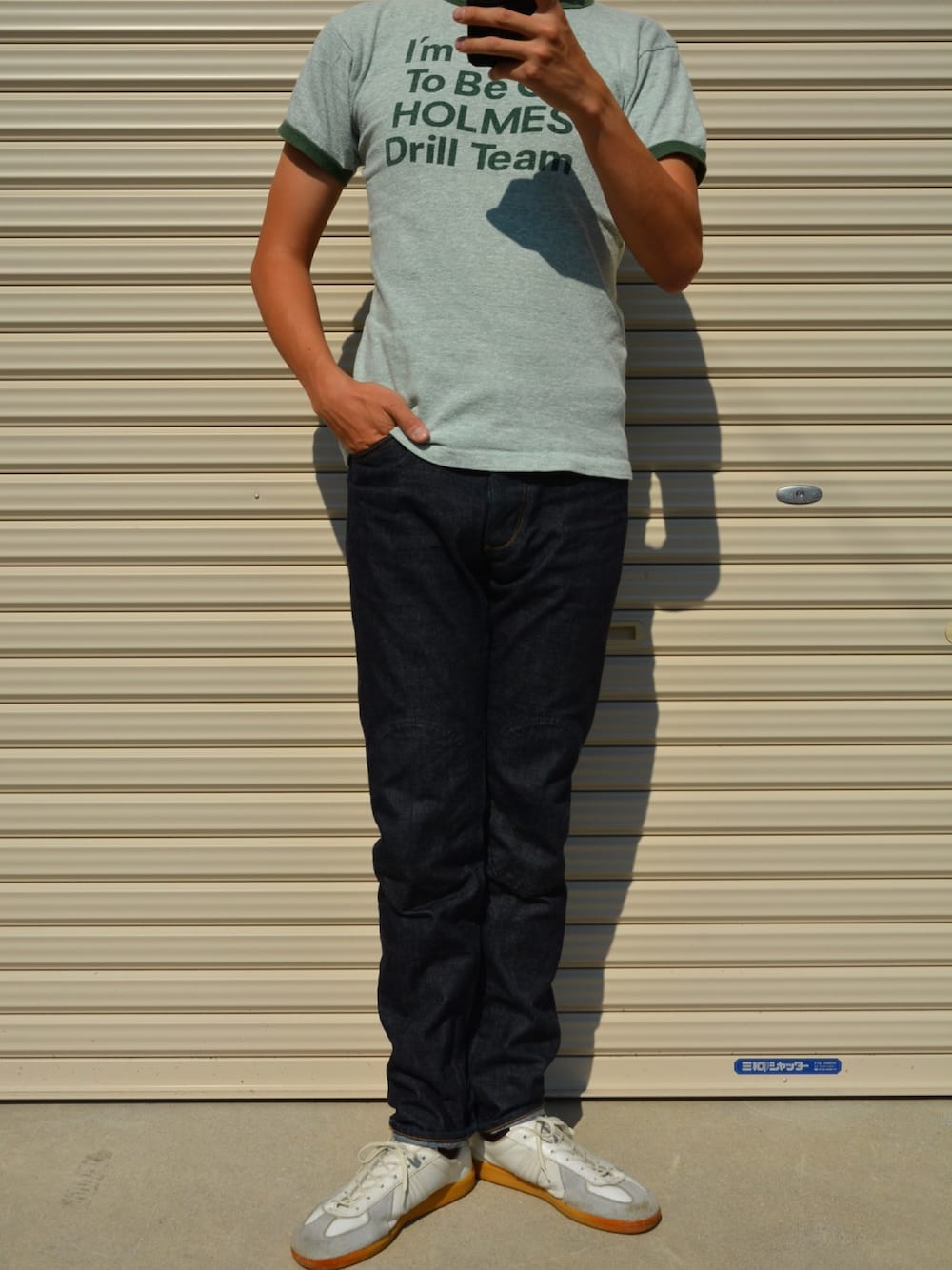 ブルー系のデニムパンツ、ホワイト系のスニーカー、グリーン系のTシャツ/カットソーを着用したメンズの秋コーディネートの1枚目の写真