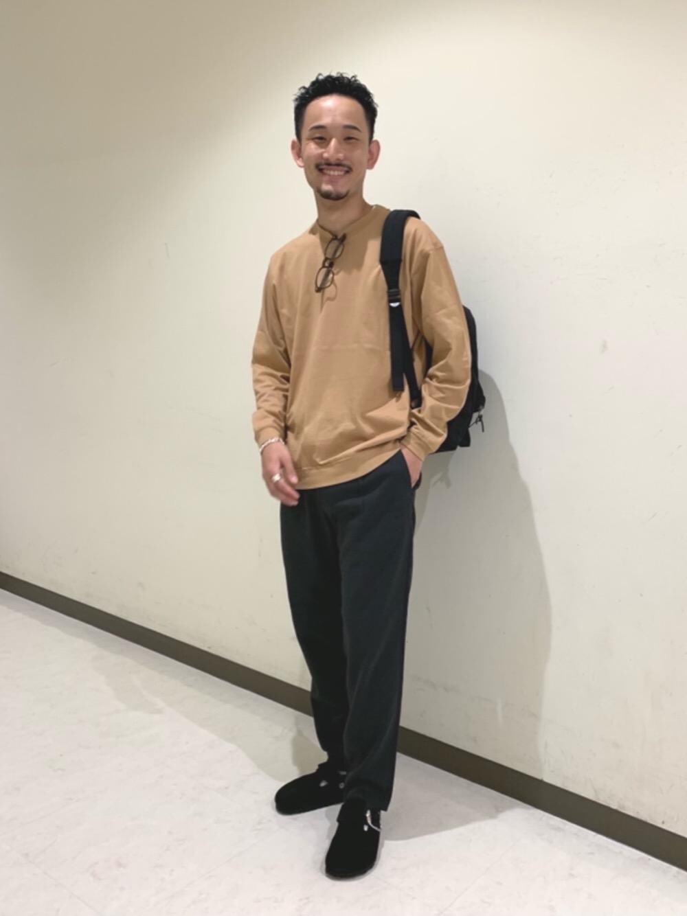 ブラック系のバックパック/リュック、ブラック系のサンダル、ブラウン系のTシャツ/カットソーを着用したメンズの秋コーディネートの1枚目の写真