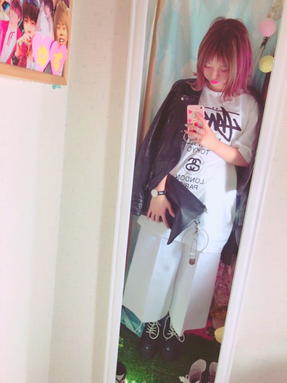 ホワイト系のTシャツ/カットソー、ブラック系のライダースジャケット、ブラック系のクラッチバッグを着用したレディースの春コーディネートの1枚目の写真