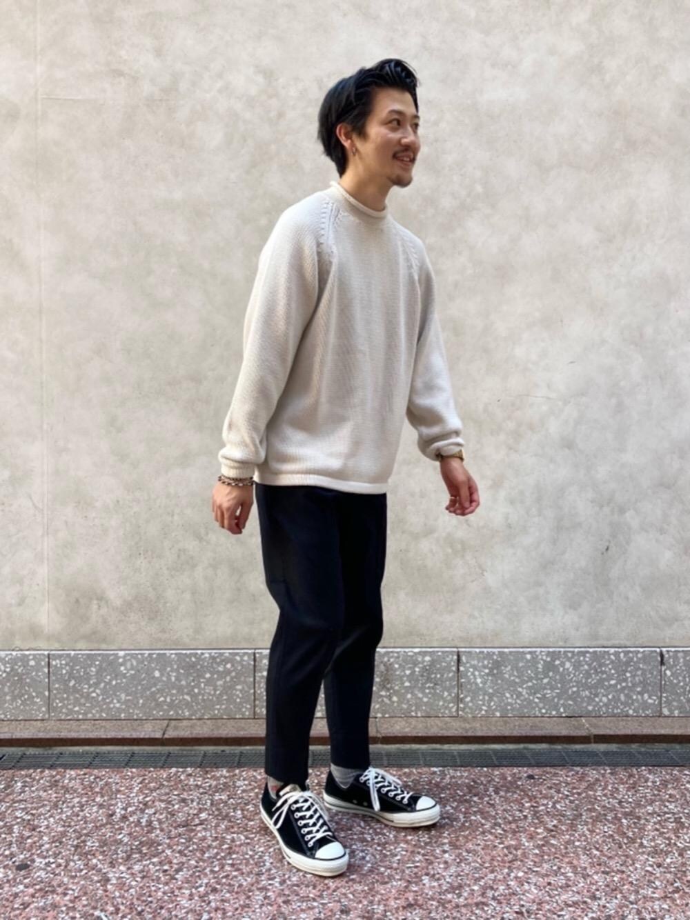 ベージュ系のニット/セーター、ブラック系のスニーカーを着用したメンズの秋コーディネートの1枚目の写真