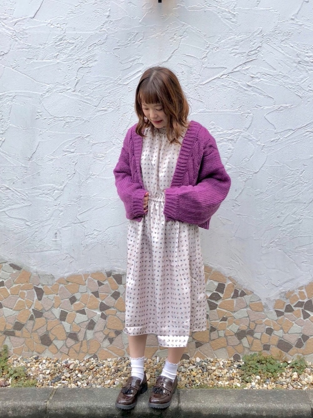 パープル系のトップス、ホワイト系のワンピースを着用したレディースの秋コーディネートの1枚目の写真