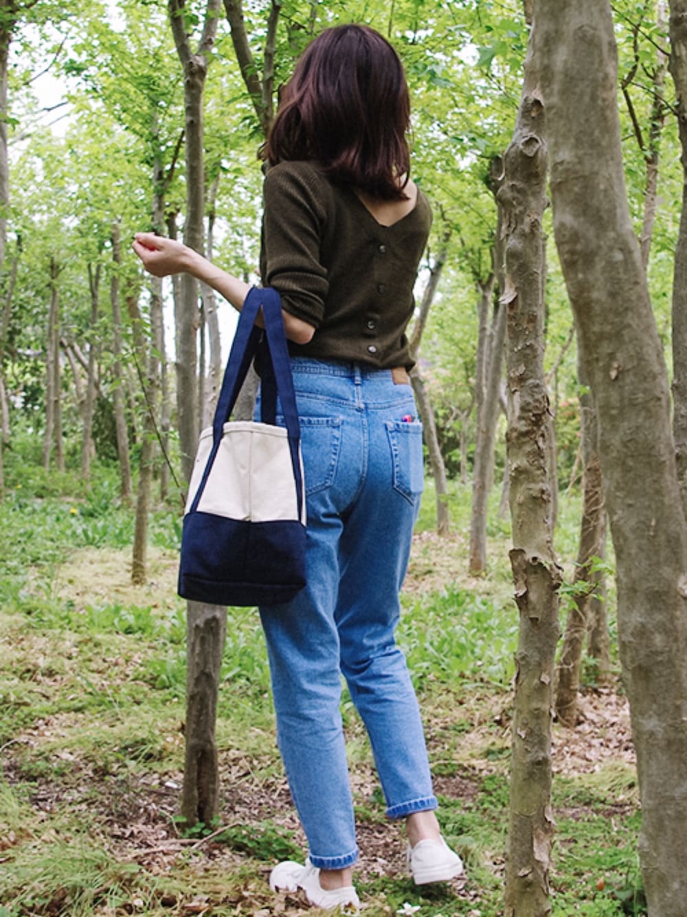 ブルー系のデニムパンツ、ブルー系のトートバッグ、グリーン系のニット/セーターを着用したレディースの夏コーディネートの1枚目の写真