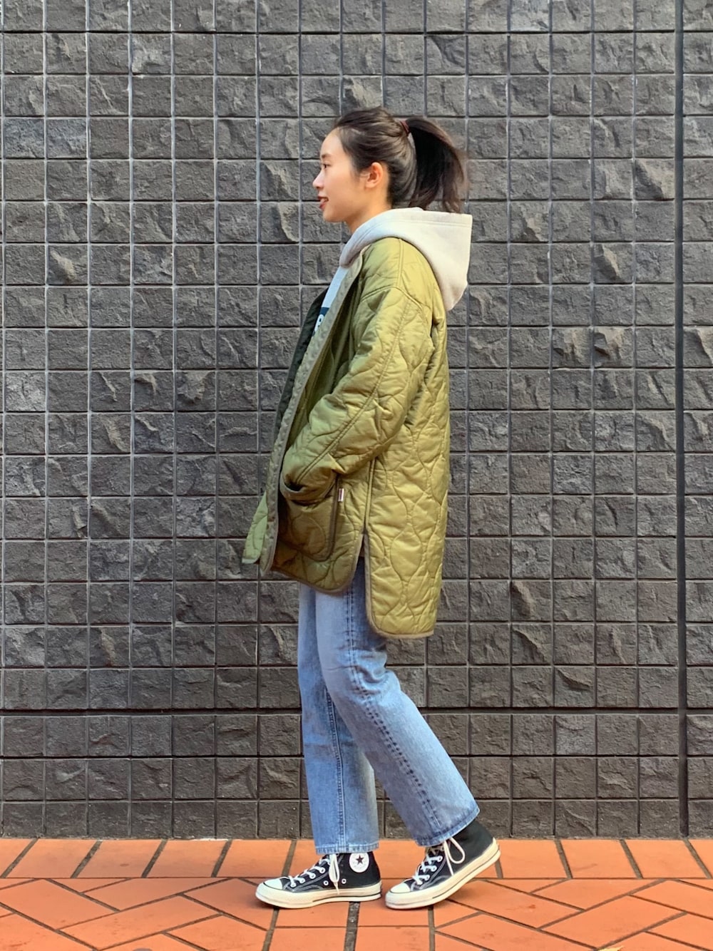 ブルー系のデニムパンツ、グリーン系のミリタリージャケット、ブラック系のスニーカーを着用したレディースの冬コーディネートの1枚目の写真