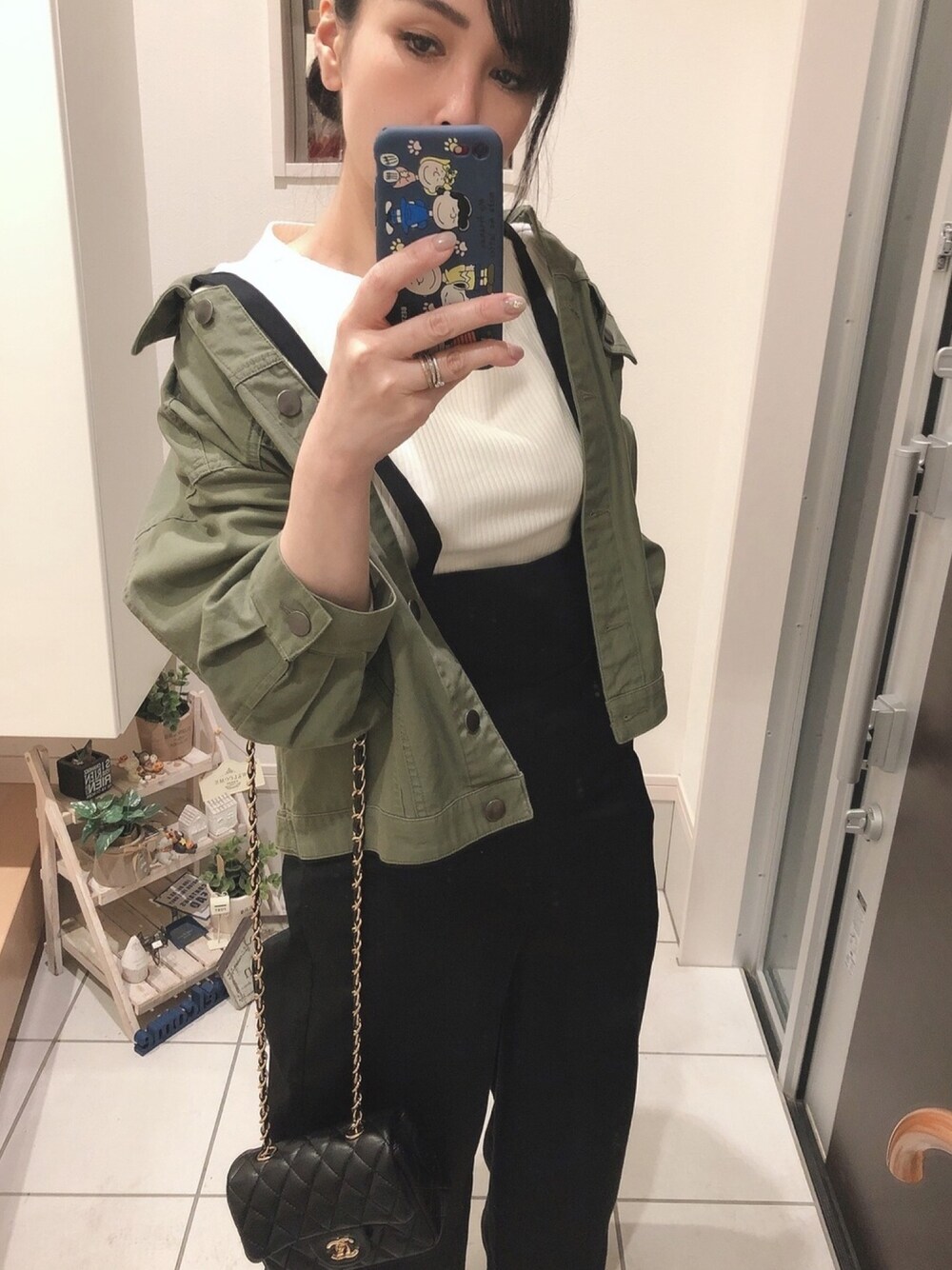 ホワイト系のニット/セーター、ブラック系のオールインワン・サロペット、グリーン系のデニムジャケットを着用したレディースの春コーディネートの1枚目の写真