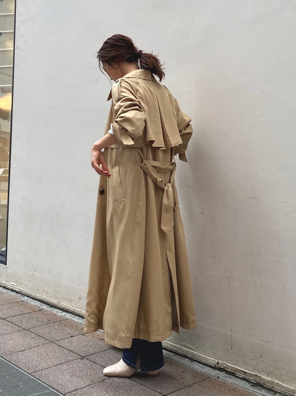 ベージュ系のトレンチコート、ブルー系のデニムパンツ、ホワイト系のブーツを着用したレディースの秋コーディネートの1枚目の写真