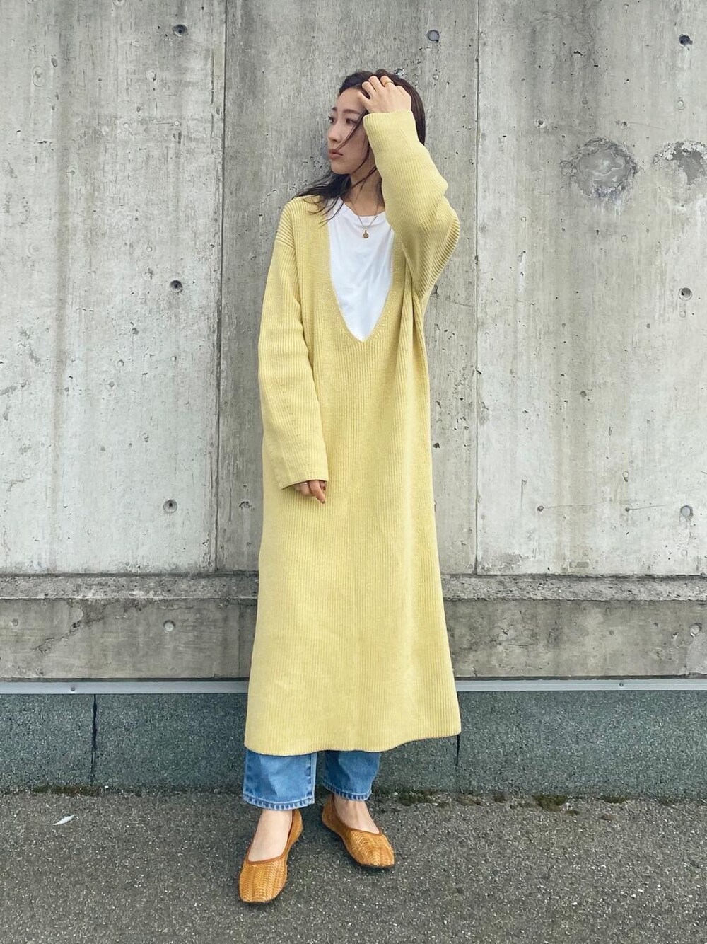 イエロー系のワンピース、ブラウン系のその他シューズ、ブルー系のデニムパンツを着用したレディースの冬コーディネートの1枚目の写真