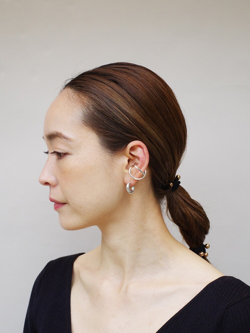 シルバー系のピアス（片耳用）、シルバー系のイヤーカフを着用したレディースの春コーディネートの1枚目の写真