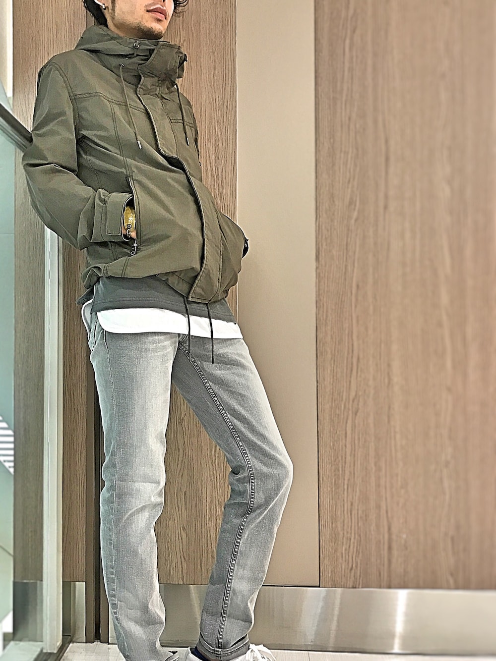 グリーン系のマウンテンパーカー、グレー系のTシャツ/カットソー、ホワイト系のタンクトップを着用したメンズの春コーディネートの1枚目の写真