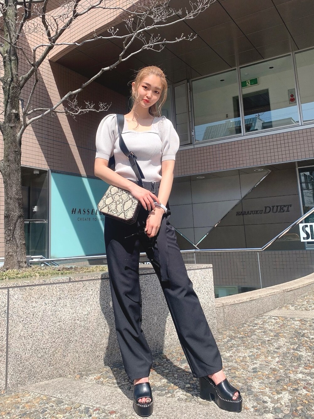 グレー系のニット/セーター、ベージュ系のショルダーバッグ、ブラック系のその他パンツを着用したレディースの春コーディネートの1枚目の写真