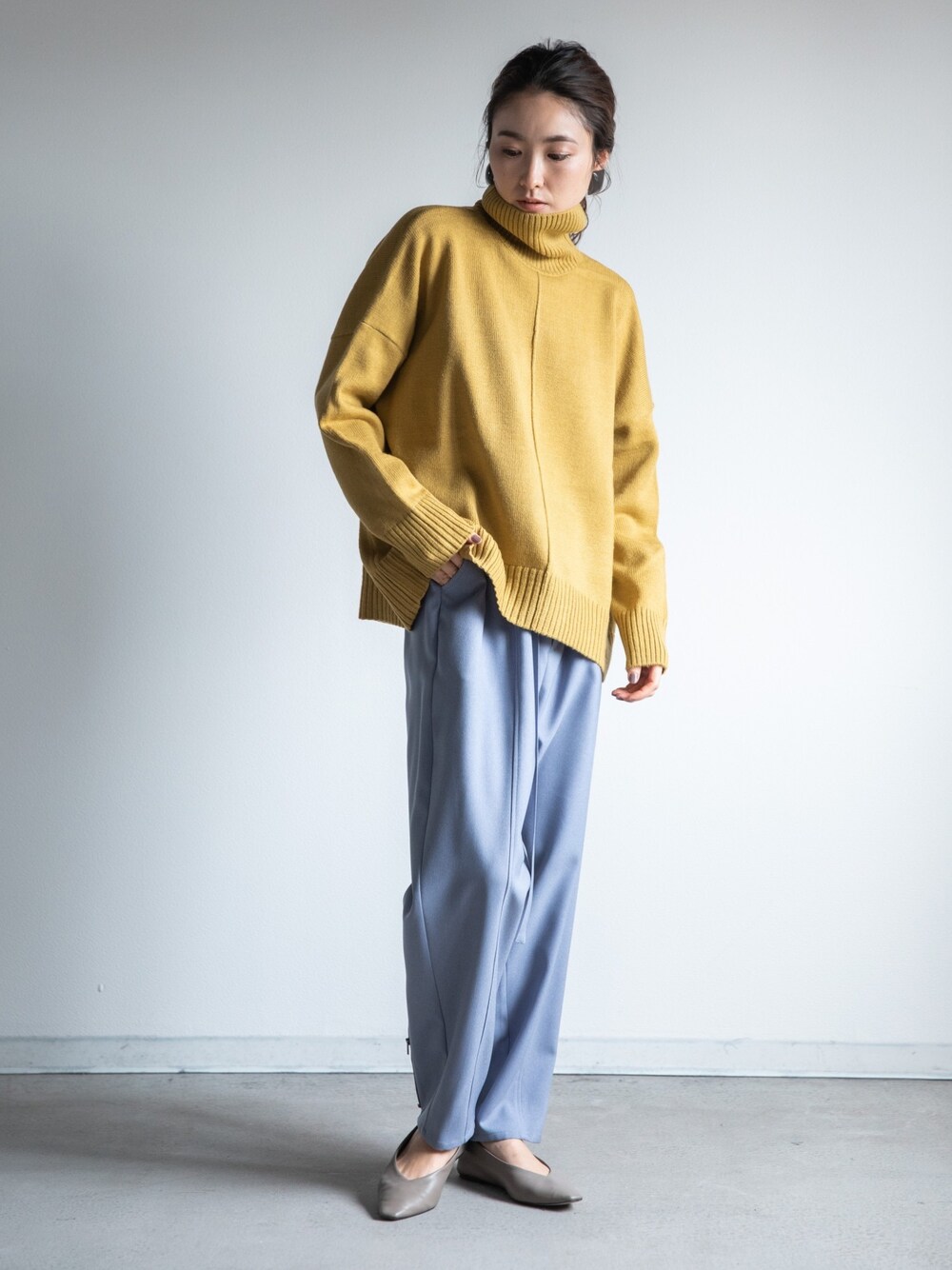グリーン系のニット/セーター、ブルー系のその他パンツ、グレー系のシューズを着用したレディースの冬コーディネートの1枚目の写真