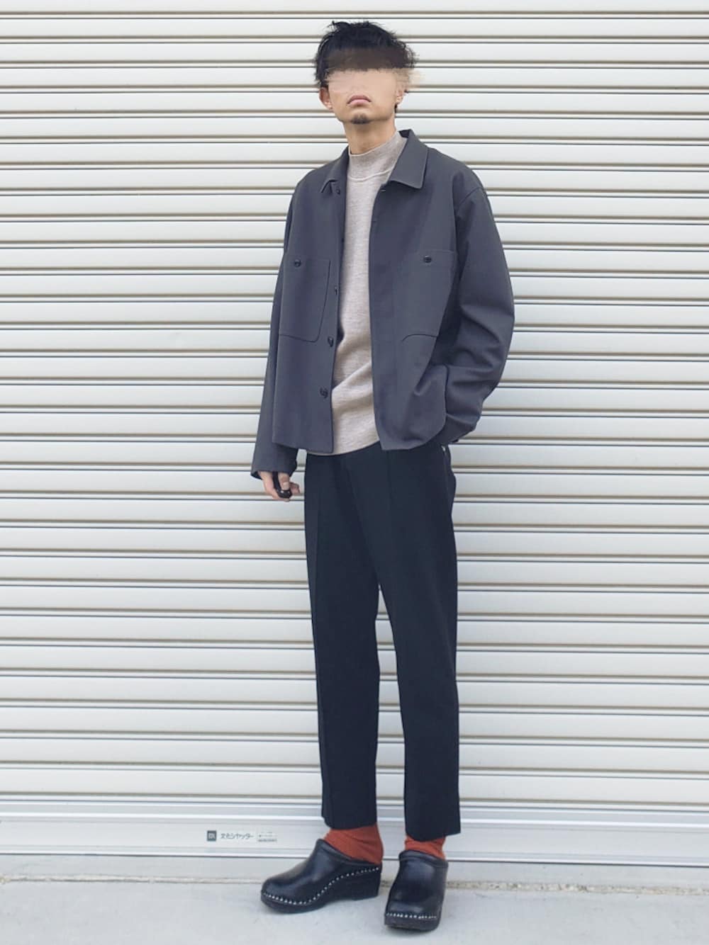 グレー系のカバーオール、ベージュ系のニット/セーター、ブラック系のパンツを着用したメンズの秋コーディネートの1枚目の写真