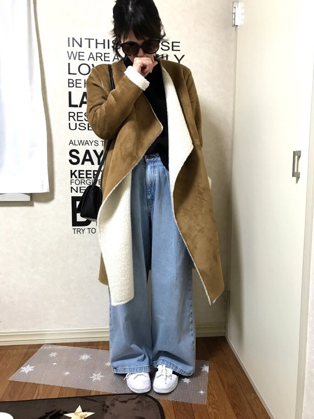 ブルー系のデニムパンツ、ホワイト系のスニーカー、ブラウン系のムートンコートを着用したレディースの冬コーディネートの1枚目の写真