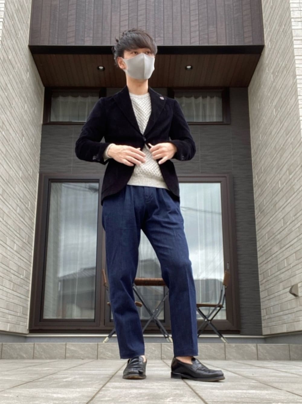 ブルー系のデニムパンツ、ブラック系のスーツセット、ベージュ系のニット/セーターを着用したメンズの春コーディネートの1枚目の写真