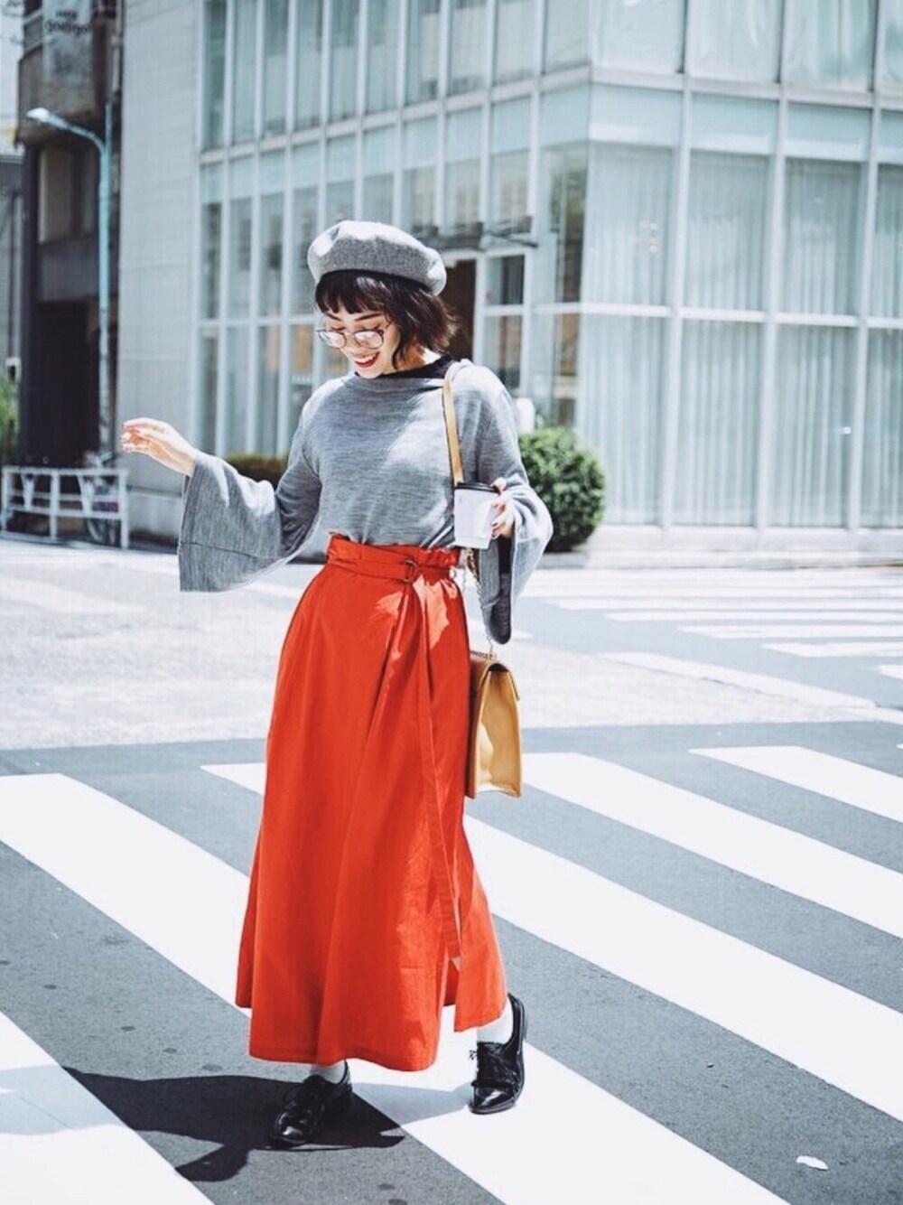 グレー系のニット/セーター、レッド系のスカート、ベージュ系のショルダーバッグを着用したレディースの夏コーディネートの1枚目の写真