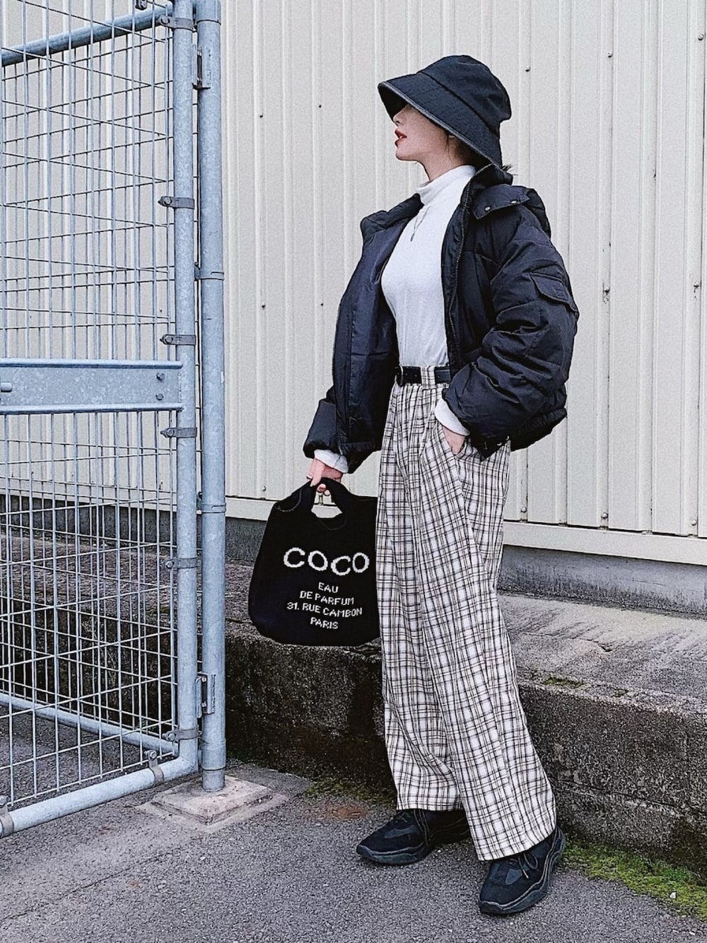 ホワイト系のトップス、ブラック系のダウンジャケット/コート、ベージュ系のパンツを着用したレディースの冬コーディネートの1枚目の写真