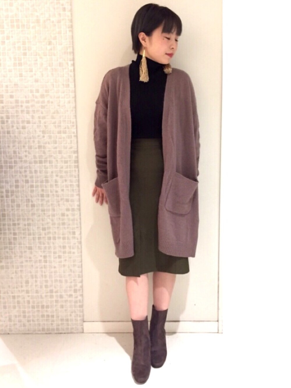 ベージュ系のカーディガン/ボレロ、ブラック系のニット/セーター、グリーン系のスカートを着用したレディースの秋コーディネートの1枚目の写真
